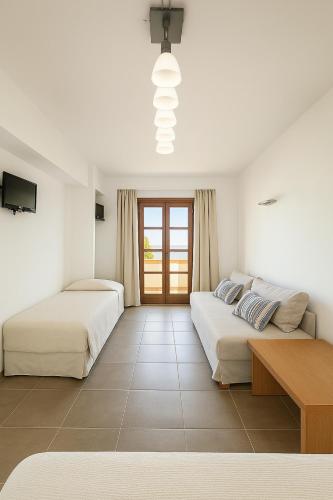 a bedroom with two beds and a table in it at Enosis Apartments - Kalypso Beach Flat in Agia Anna Naxos