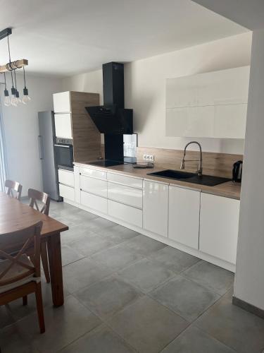 une cuisine avec des armoires blanches, une table et un évier dans l'établissement Maison Sorgues, à Sorgues