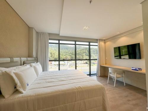 イタペマにあるSuíte com vista para montanhas no Blue Sea Hotel, beira-mar+lazer completoのベッドと机とテレビのある寝室