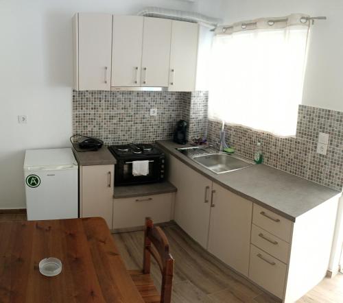 a kitchen with white cabinets and a wooden table at Philoxenia Apartments in Kryonéri