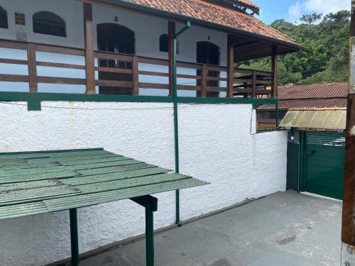 a green picnic table in front of a building at Suítes Aconchego dos Pinhais in Santo Antônio do Pinhal
