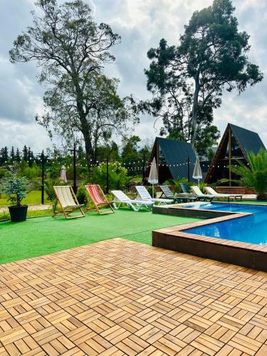 a patio with lawn chairs and a swimming pool at Eucalyptus Cottages in Chakvi