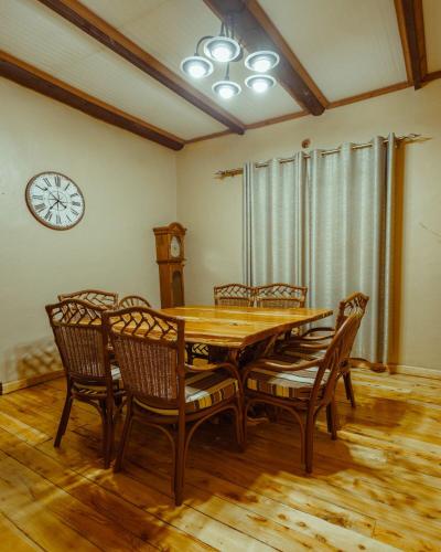 a dining room table with chairs and a clock on the wall at Thitu Log House in Nakuru
