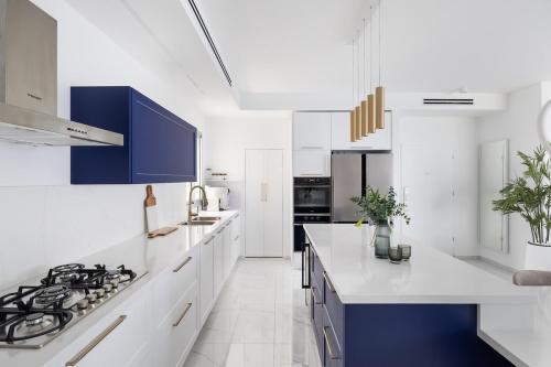 a kitchen with white counters and blue cabinets at JY Luxury penthouse in Ashqelon