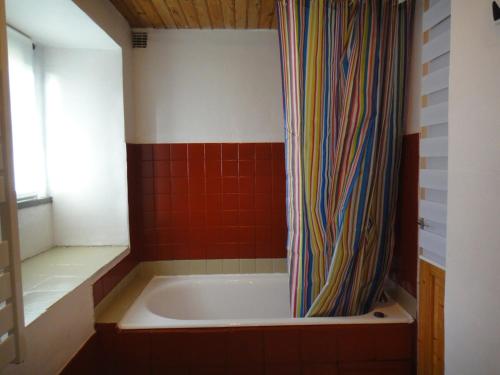 La salle de bains est pourvue d'une baignoire avec un rideau de douche coloré. dans l'établissement Gîte des Hortensias - Old farmhouse - Sea view, à Carantec