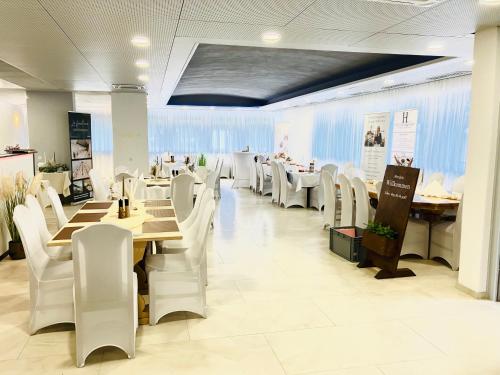 a dining room with white chairs and tables in a restaurant at La Frontiera Hotel & Eventlocation - idyllisch, nah' der Schweiz - zum Rheinfall bei Schaffhausen in Tengen