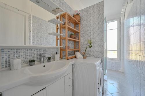 Un baño blanco con lavabo y espejo. en Appartement spacieux avec hamac + parking gratuit, en Gentilly