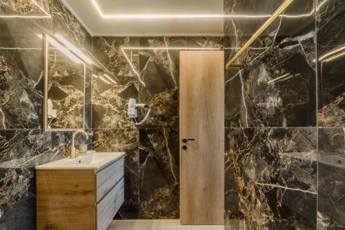 a bathroom with a sink and black marble walls at LIOSTASI luxury suites in Tragána