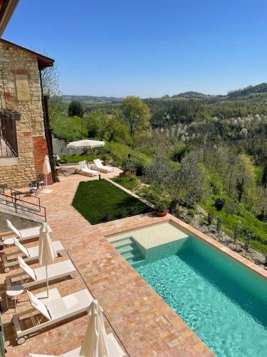 a swimming pool in a yard with chairs and a building at Relais Dal Cavaliere in Castellino