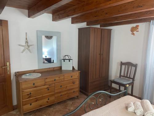 a bedroom with a dresser and a mirror and a chair at La Casa degli Enzi in Portoscuso