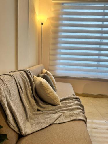 a blanket sitting on top of a couch next to a window at Apartamento en Manizales - Chipre in Manizales