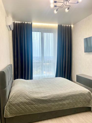 a bedroom with a bed with blue curtains and a window at Апартаменти Люкс, Центр, ЖК Яровиця,Паркомісце in Luts'k
