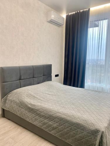 a bedroom with a bed and a window with blue curtains at Апартаменти Люкс, Центр, ЖК Яровиця,Паркомісце in Luts'k