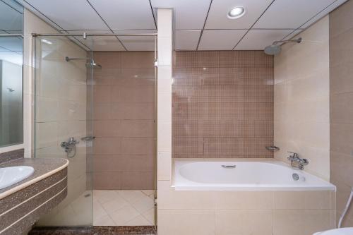 a bathroom with a tub and a shower and a sink at Beachfront holiday homes with beach,sauna,jacuzzi,cafe,restaurants and more in Ajman
