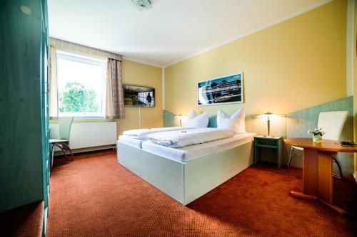 ein Schlafzimmer mit einem Bett in einem Zimmer mit einem Fenster in der Unterkunft Parkhotel Senftenberg in Senftenberg