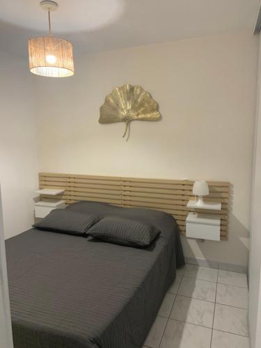 - une chambre dotée d'un lit avec une feuille sur le mur dans l'établissement Les Anglade, au Lavandou