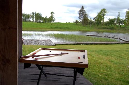 a ping pong table sitting on a deck next to a pond at Pūjalgi in Ēdole