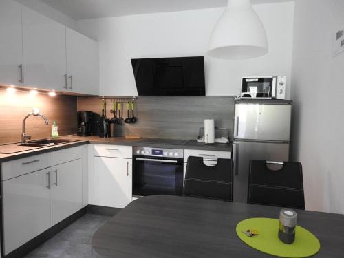a kitchen with white cabinets and black appliances at Urlaub mit Sauna und Pool ist cool! in Bad Harzburg