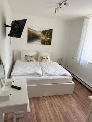 a white bedroom with a bed and a desk at Wohnen am Reiterhof, 50 qm, mit Gartennutzung in Hagen