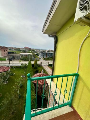 a balcony of a yellow building with a green railing at VilaHasa in Tërbuf