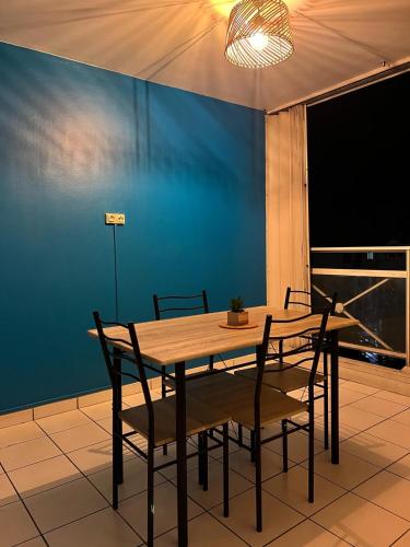 a dining room table with chairs and a blue wall at Blue Paradise appartement 1 chambre central à Fort-de-France in Fort-de-France
