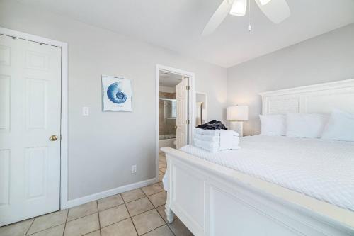 a white bedroom with a white bed and a ceiling fan at Paradise Duplex A in Gulf Shores