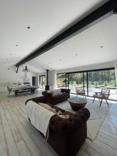 un ampio soggiorno con un grande divano e tavoli di La Villa des Chênes ad Audenge