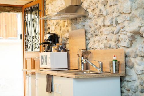 une cuisine avec un évier et un micro-ondes dans l'établissement Studio L'Échappée du Chapeau Rouge, à Saint-Antoine