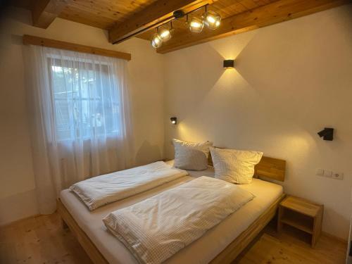 a bedroom with a bed with white sheets and a window at Inntal Alpin Apartments - Niedere Munde in Telfs