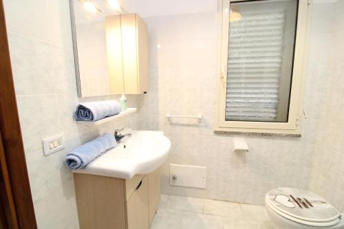a white bathroom with a sink and a toilet at Farri's Apartment in La Caletta
