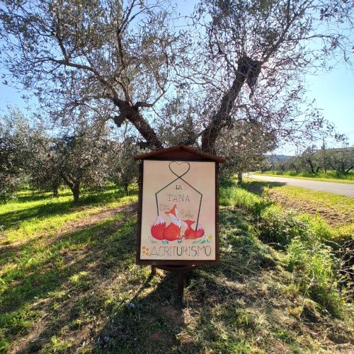 a sign in the grass in front of a tree at Agriturismo La tana della volpe in Alberese