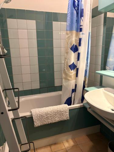 La salle de bains est pourvue d'une baignoire verte et blanche ainsi que d'un lavabo. dans l'établissement cottage cosy du golf avec piscine, à Ploemel