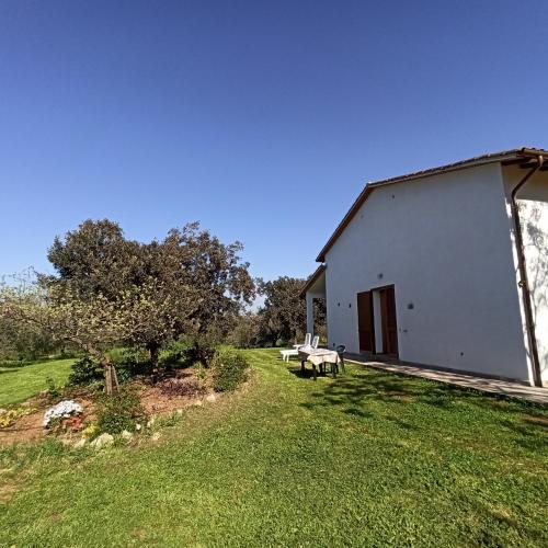 a white building with a picnic table in a yard at Agriturismo La tana della volpe in Alberese