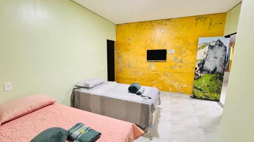 a bedroom with two beds and a yellow wall at Pousada coração do Jalapão in São Félix do Tocantins