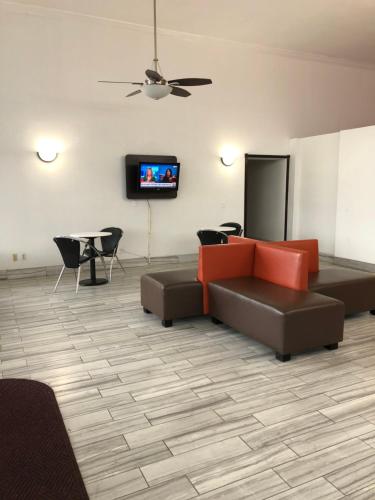 a living room with a couch and a tv on a wall at Motel 6-Daytona Beach, FL - Speedway in Daytona Beach