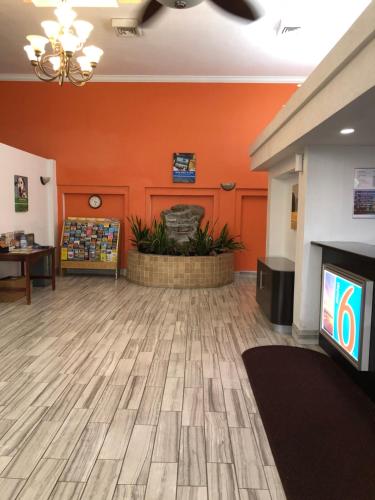 a lobby with an orange wall and a flat screen tv at Motel 6-Daytona Beach, FL - Speedway in Daytona Beach