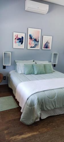 a large bed in a room with pictures on the wall at Chalé de alto padrão em condomínio in Santa Rita do Sapucaí