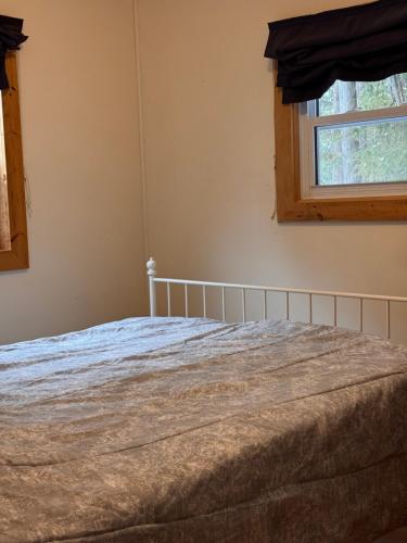 a bed in a bedroom with a window at The Shady Pine at New Frontiers Retreat in Eganville