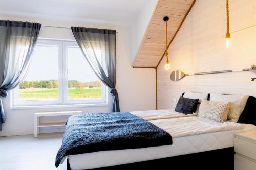 a bedroom with a bed and a large window at Cichy Domek Karwia - Apartamenty - Basen, Jacuzzi, Sauna in Karwia