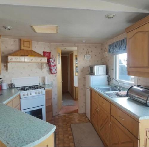 a small kitchen with a stove and a sink at 104-2 coral beach 8 berth 4 ADULTS MAX LEAD PERSON MUST BE OVER 30 in Ingoldmells