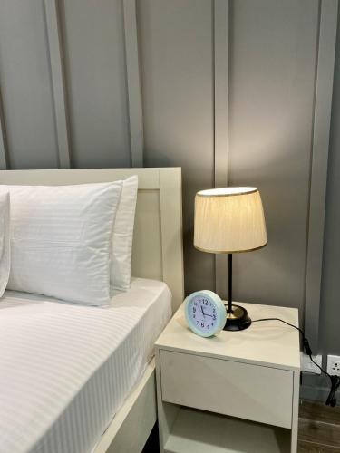 a bed with a lamp and a clock on a night stand at PENTASQUARE Apartments by SUPERHOST STAYS in Lahore