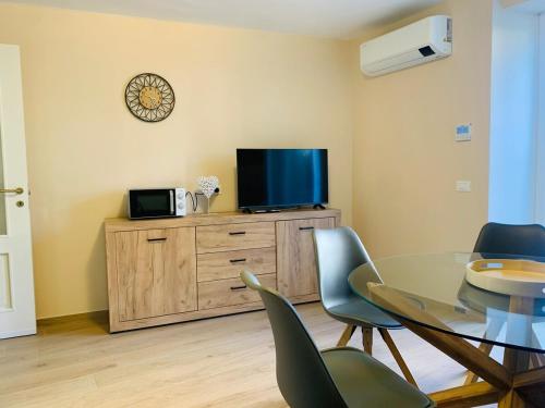 a dining room with a table and chairs and a tv at Ca' dal Pum - Lake Orta - Elegant holiday home in Gozzano