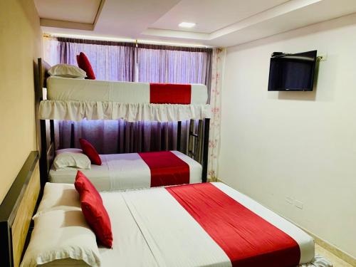 two beds in a room with red and white at Hotel Bisou in Cali