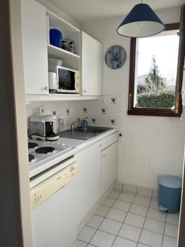 a kitchen with white cabinets and a sink and a window at Fleur d'eau in La Tranche-sur-Mer