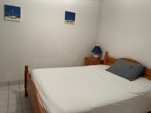 a bedroom with a white bed with a blue pillow at Fleur d'eau in La Tranche-sur-Mer