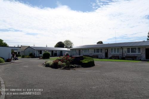 a building with a parking lot in front of it at Garden Court Motel & Backpackers in Tauranga