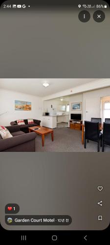 a living room with a couch and a table at Garden Court Motel & Backpackers in Tauranga
