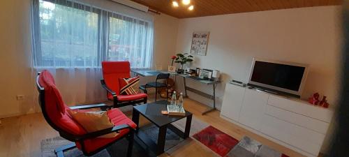 a living room with red chairs and a flat screen tv at Ferien- und Business Wohnung in Mönsheim