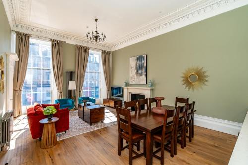 a living room with a table and a dining room at Dragon Suites Luxury Apartments at 9 Albyn Place in Edinburgh