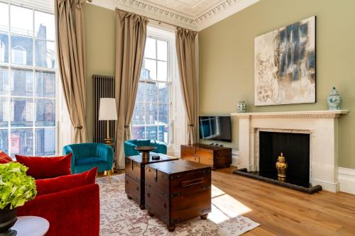 a living room with a red couch and a fireplace at Dragon Suites Luxury Apartments at 9 Albyn Place in Edinburgh